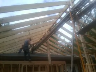 Rafters going up over a new addition with a worker on the wall in Tuscarora