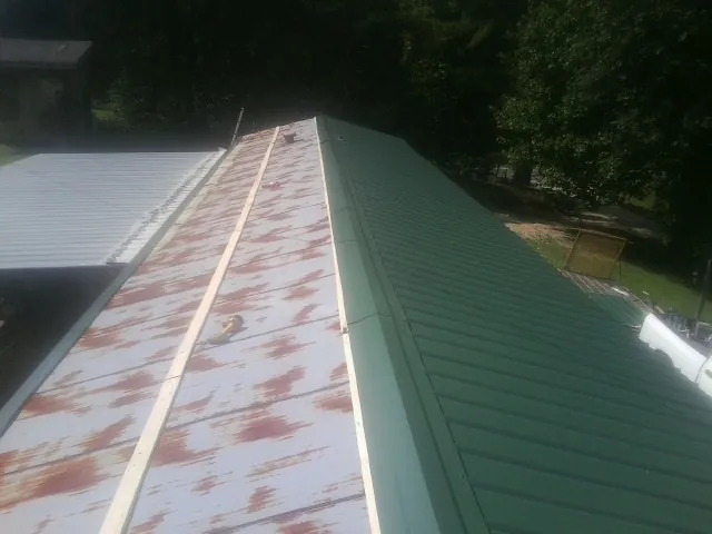 Old rusted panels beside newly installed green metal roofing — Wind Damage Roof Repair by Roofing Brothers in Tuscarora