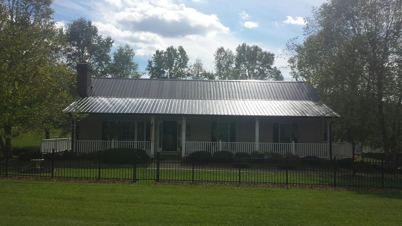 Gray metal roof on a brick ranch with a full width front porch — Gutter Guard Installation work by our crew in Tuscarora
