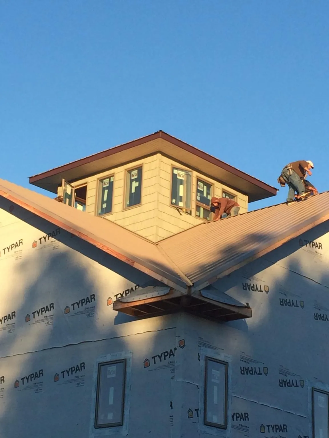 Roofers working around a rooftop cupola on a new metal roof at sunset — Roof Waterproofing in Tuscarora by Roofing Brothers